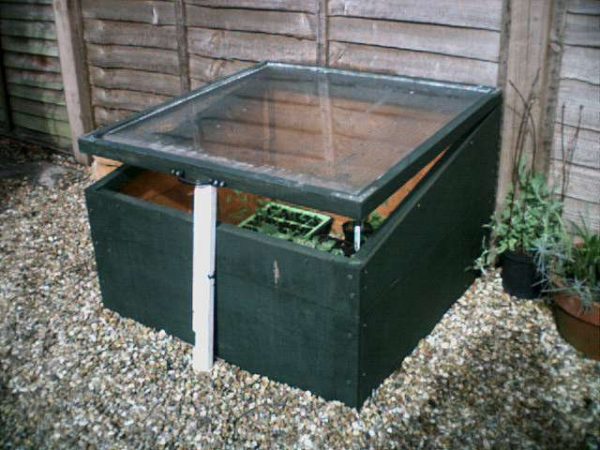 A cold frame propped open with a piece of PVC