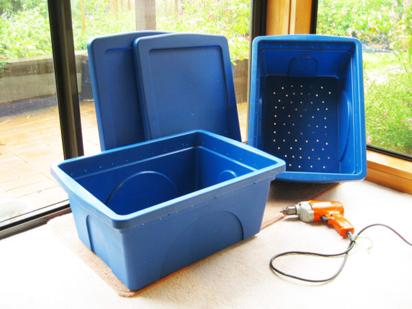 Vermicomposting set up with blue plastic bins and a drill