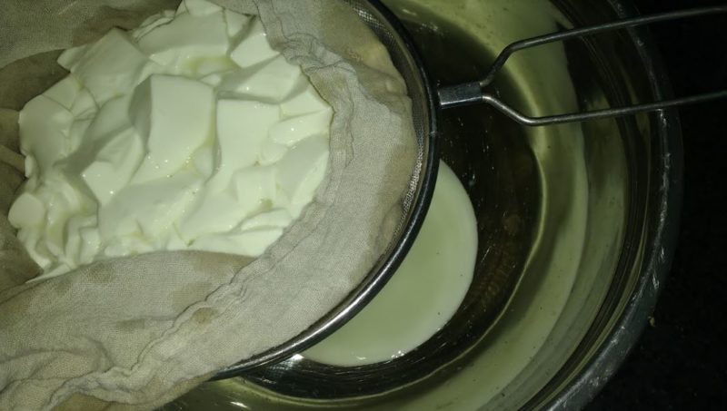 The goat cheese being strained