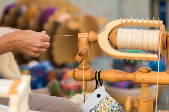 Person spinning wool into yarn on a spinning wheel
